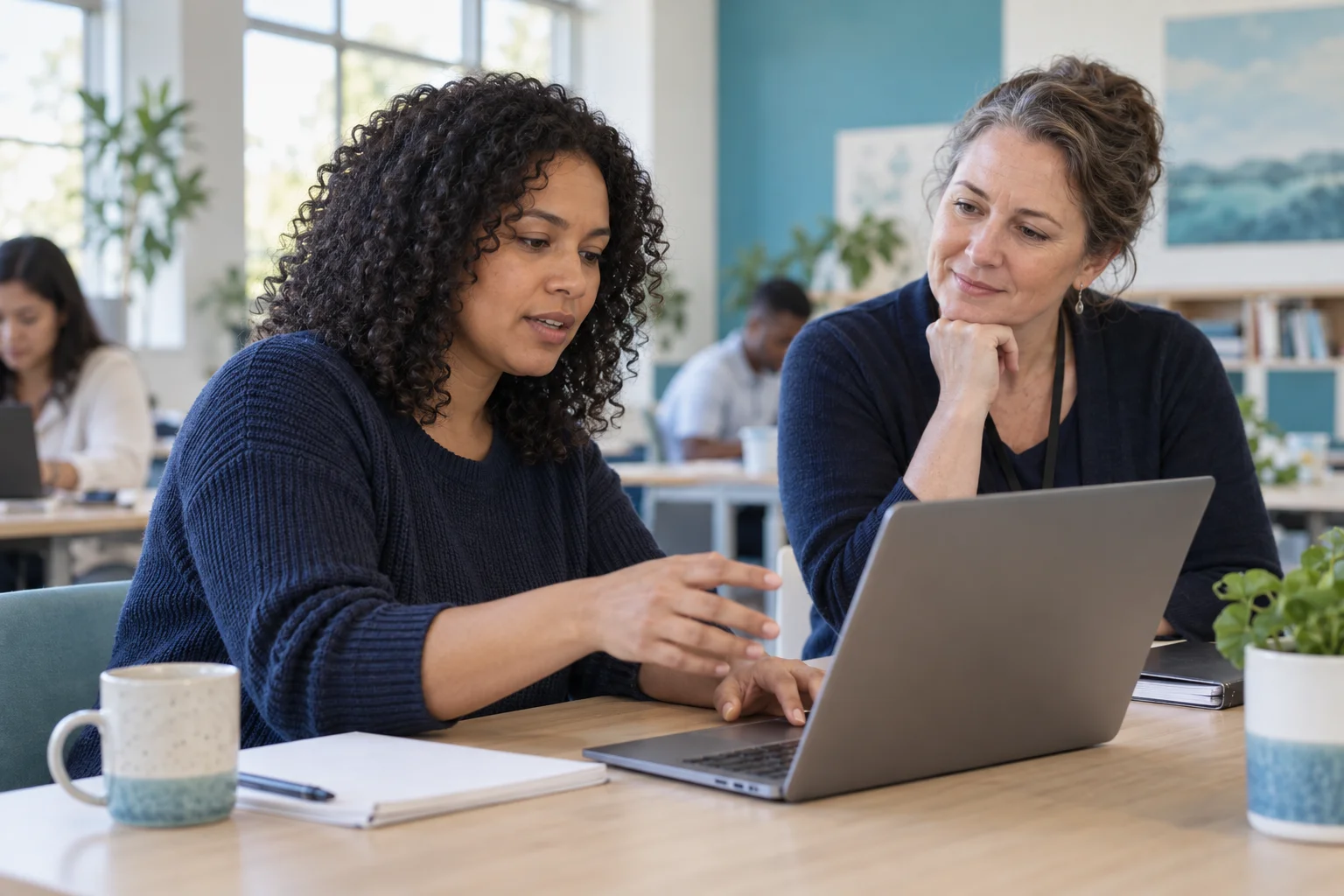 An adult learner discussing a laptop activity with an instructor.